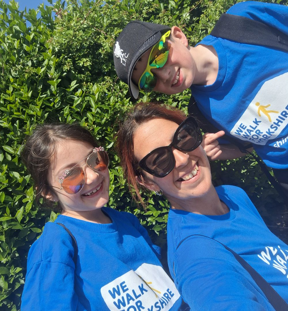 A lady, girl and boy in sunglasses smile at the camera