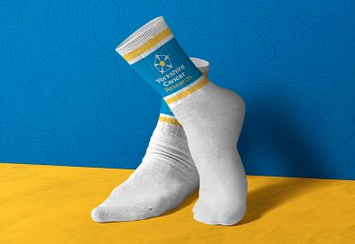 White sports socks with blue and yellow Yorkshire Cancer Research branding