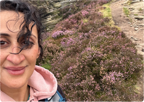 A lady takes a selfie with rocks and heather in the background