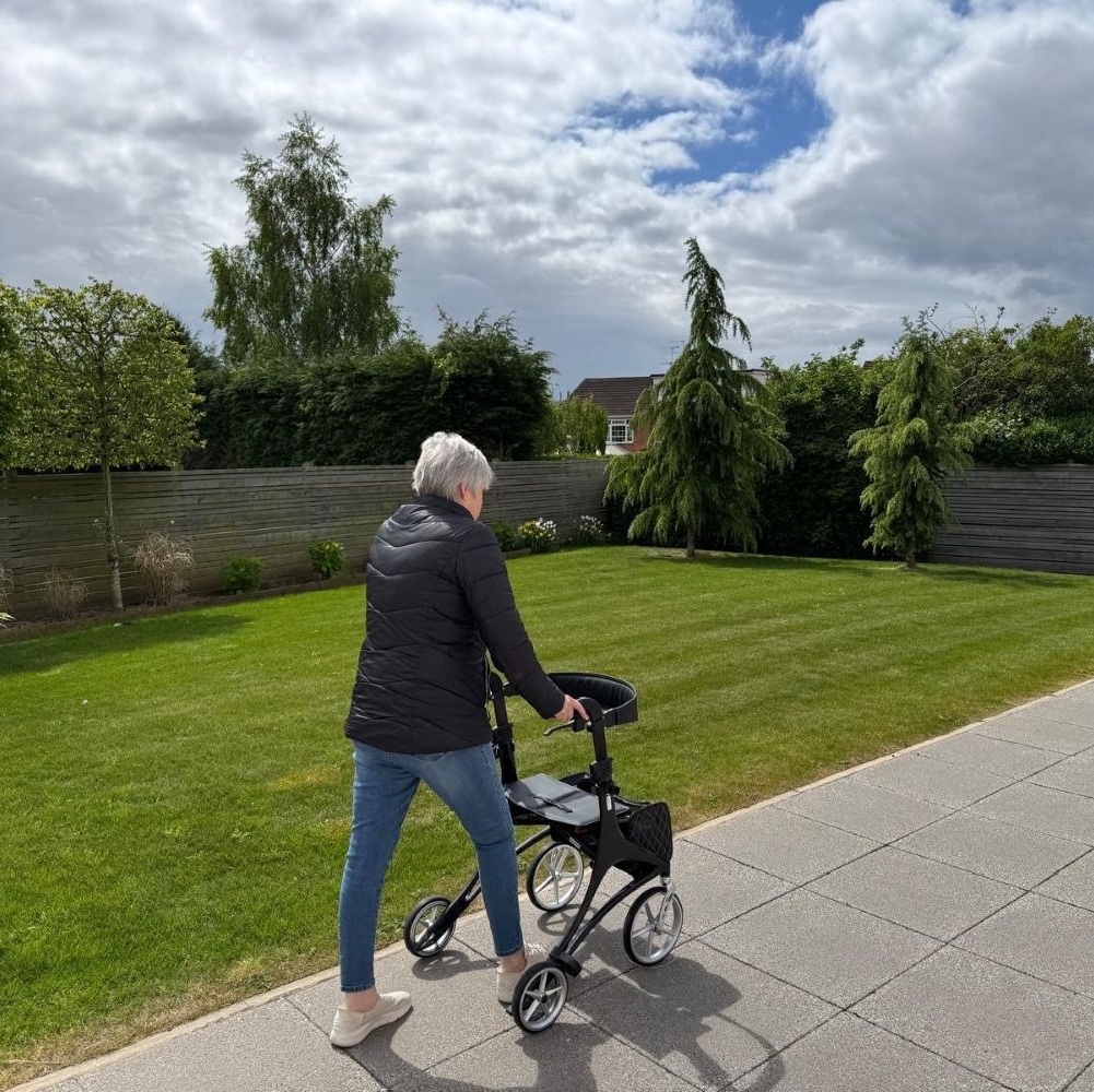 A lady using a walker to assist her crosses a patio