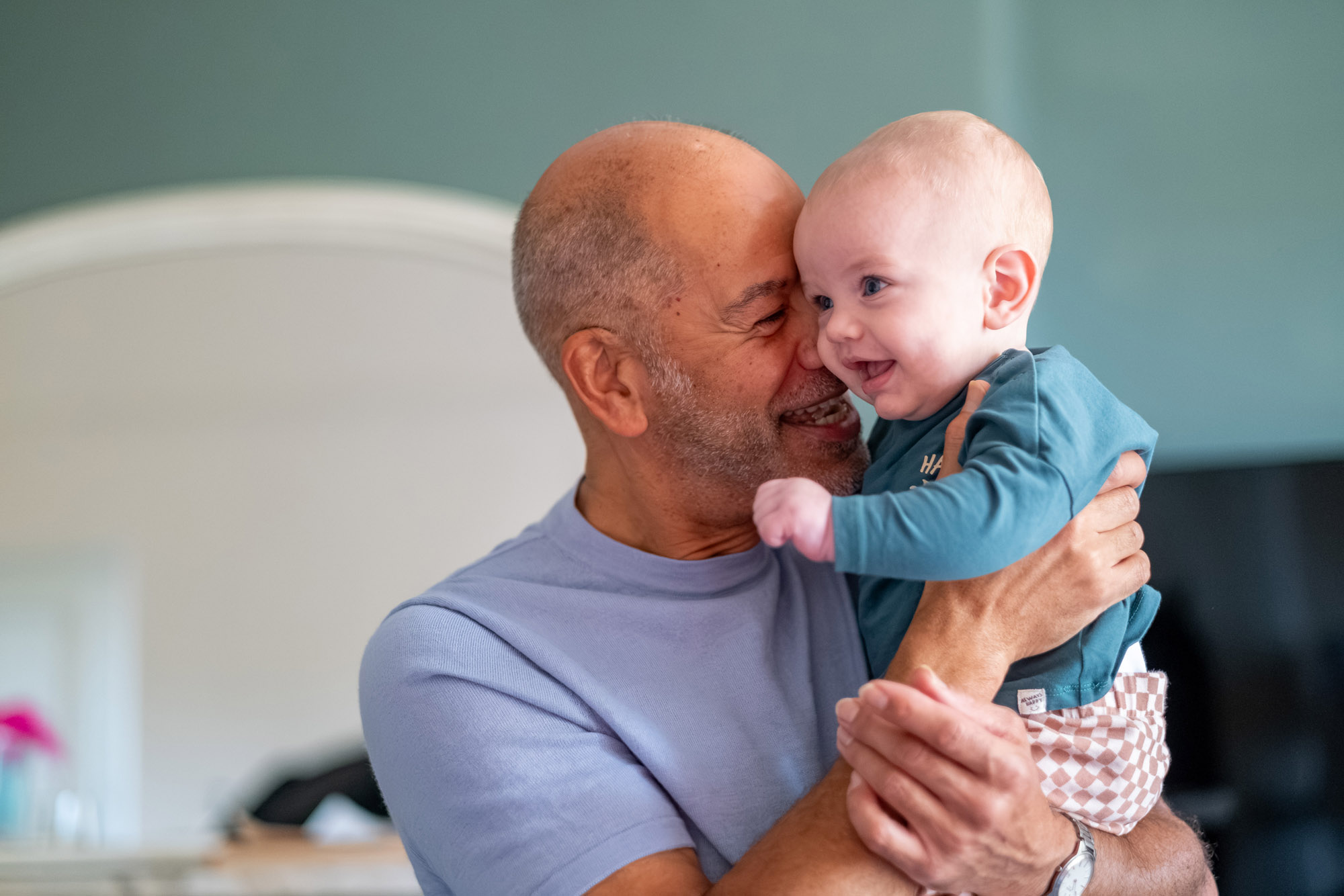 A man warmly hugs a smiling baby boy