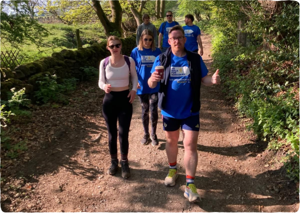 A group of people walk along a wooded track